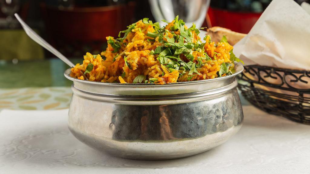 Chicken Biryani · Marinated chicken and saffron-flavored basmati rice with herbs and spices, garnished with raisins and cashews.