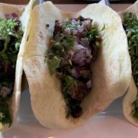 Steak Tacos Al Carbon · Three grilled steak tacos with onions and cilantro. Served with rice, charro beans, lettuce,...