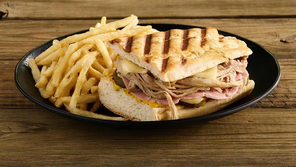 The Cuban Panini · Our awesome Cuban sandwich - Smoked pork, ham, swiss, pickles, and mustard on real Cuban bread, pressed until perfectly melted. Served with one side