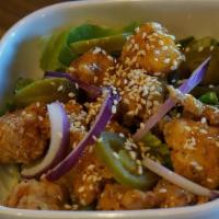 Sticky Chicky · Crispy chicken chunks tossed in apricot glaze with red onions and jalapenos, on a bed of let...
