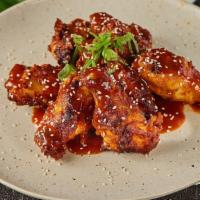Korean Chicken · Marinated and fried chicken wings covered in a soy and teriyaki sauce with sesame and chives.