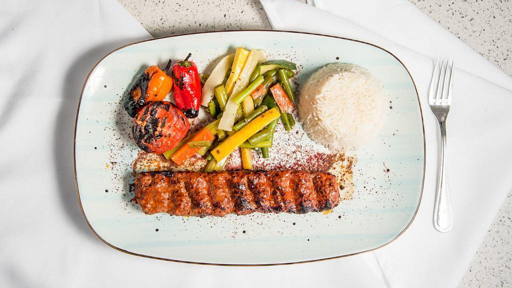 Kofte Kebab · Seasoned ground beef and lamb flavored with garlic, onions grilled on flat skewers served over lavash bread with grilled sweet peppers and tomatoes, onion salad, and basmati rice.