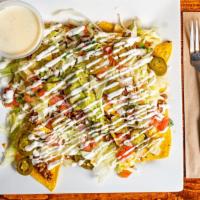 Nachos Supreme · A plate of chips covered with shredded cheese, ground beef, lettuce, sour cream, pico de gal...