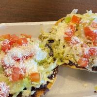 Tostada De Tinga · Served on fried tortilla, refried black beans, shredded chicken in chipotle sauce place  top...