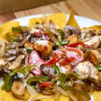Nacho Fajita Texanos · Steak, chicken and shrimp fajita nachos cooked with onions, bell peppers and tomatoes.