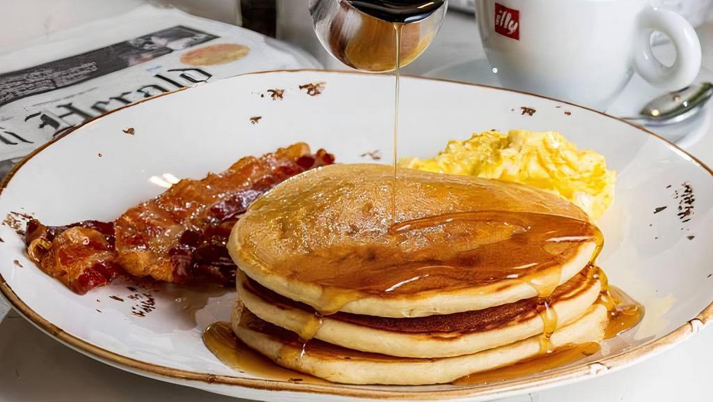 Pancakes Breakfast · With scrambled eggs and bacon, drizzled with maple syrup.