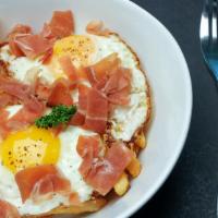 Huevos Rotos · Two eggs over french fries, topped with serrano ham, and truffle oil.