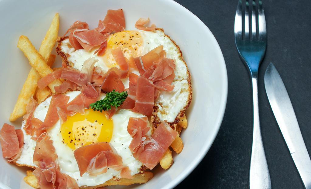 Huevos Rotos · Two eggs over french fries, topped with serrano ham, and truffle oil.