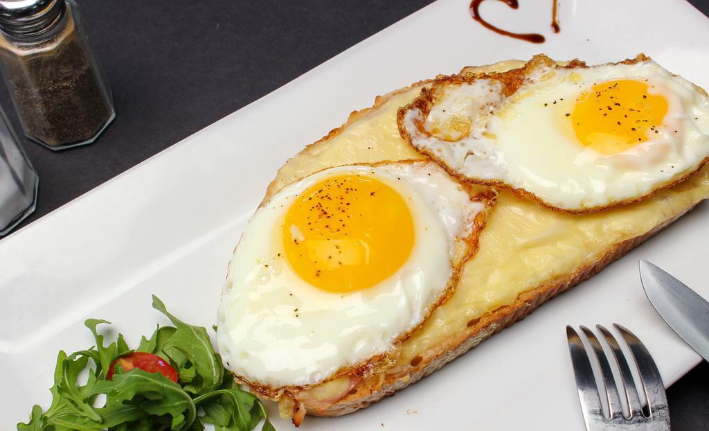 Croque Madame · A light spread of bechamel on toasted bread topped with cheese, ham, and a fried egg.
