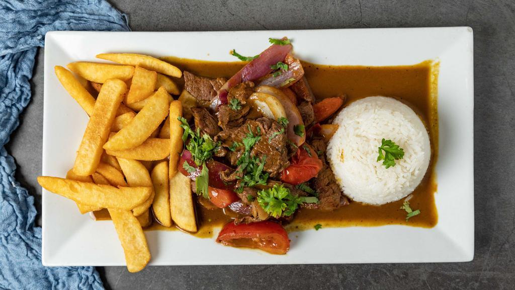 Lomo Saltado · Steak strips sautéed with onions, tomatoes and cilantro in a wine and soy sauce served with white rice and french fries.