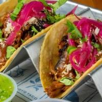 Cochinita Pibil Taco · Yucatan style achiote roasted pork, habanero pickled onions, and queso cojita. Two tacos per...
