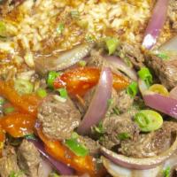 Tacu Tacu Con Lomo Saltado · A pan-fried mix of beans puree and rice with sautées steak pieces, onions, and tomatoes.