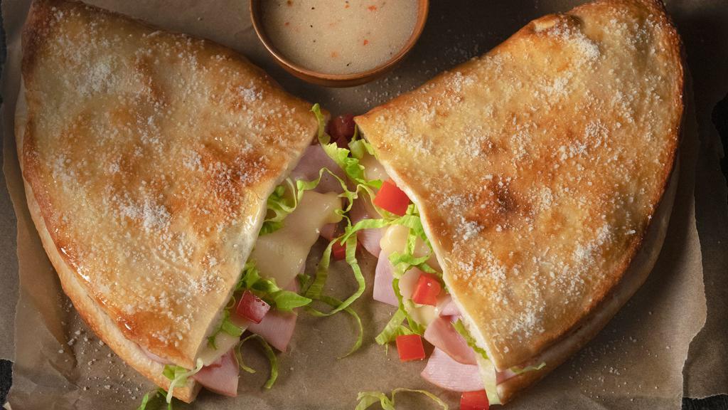 Ham & Cheese Deli Boat · Pizza dough baked into a crunchy, golden crust then topped with butter and romano. Layered with ham, provolone, lettuce & tomatoes. Served with a side of italian dressing.