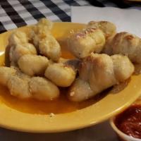 Garlic Knots · House specialty. Our homemade dough knots dripping in garlic butter. You gotta try these!