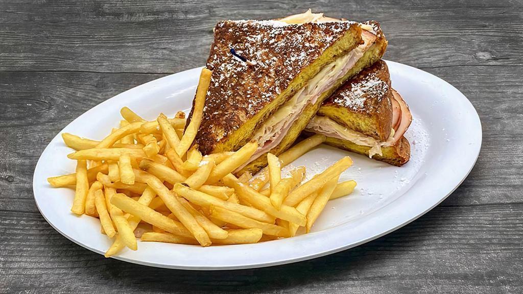 Monte Cristo Sandwich · Our Signature Challah French Toast Grilled with Sliced Turkey, Shaved Ham, and Swiss Cheese topped with Powder Sugar served with Skinny Fries.