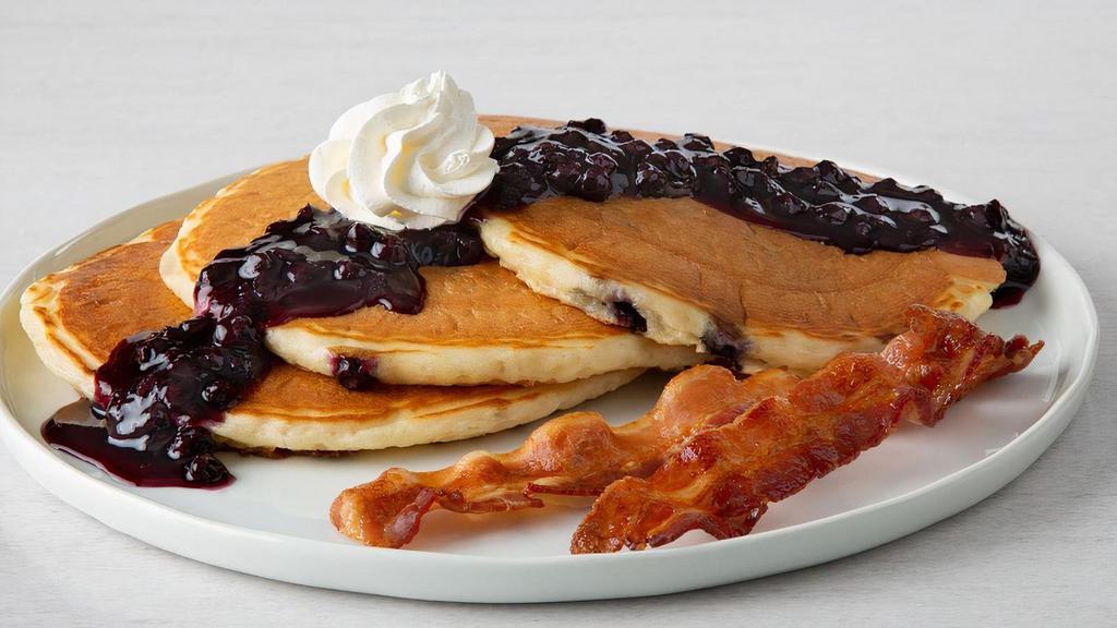 Double Blueberry Pancakes · Three buttermilk pancakes with blueberries, topped with blueberry sauce and whipped cream. Served with two cherrywood-smoked bacon strips, two sausage links or one house-made sausage patty.