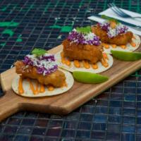 Baja Fish Tacos · Crispy white fish topped with red cabbage slaw, queso fresco and Chipotle Crema. Served on f...