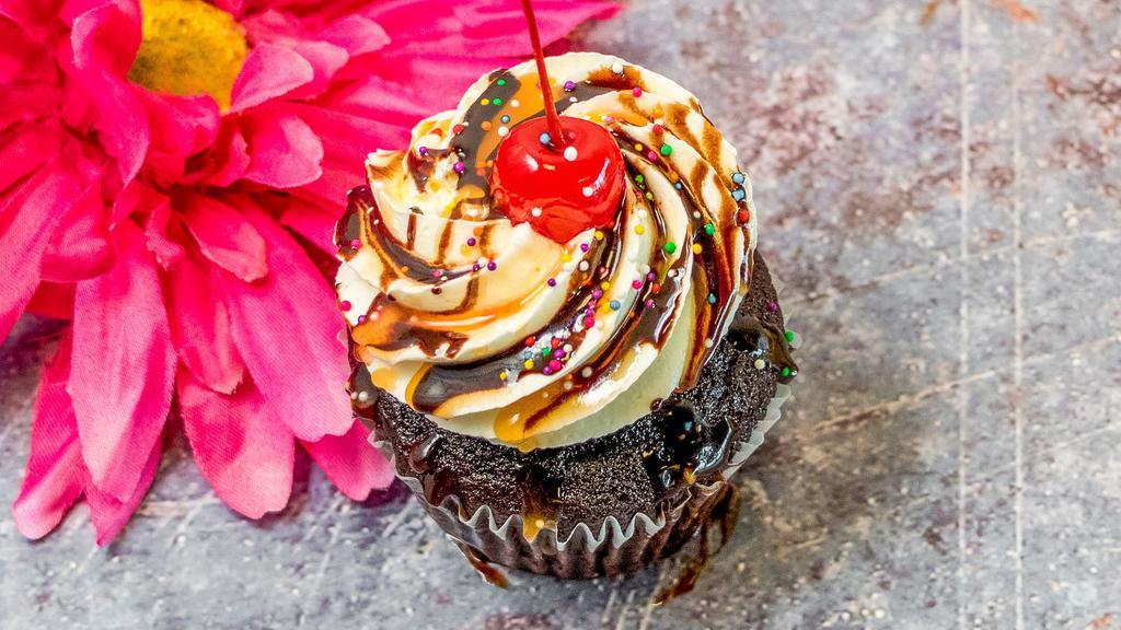 Hot Fudge Sundae · Chocolate cupcake with vanilla buttercream frosting with a chocolate and caramel drizzle, rainbow sprinkles, and a cherry on top.
