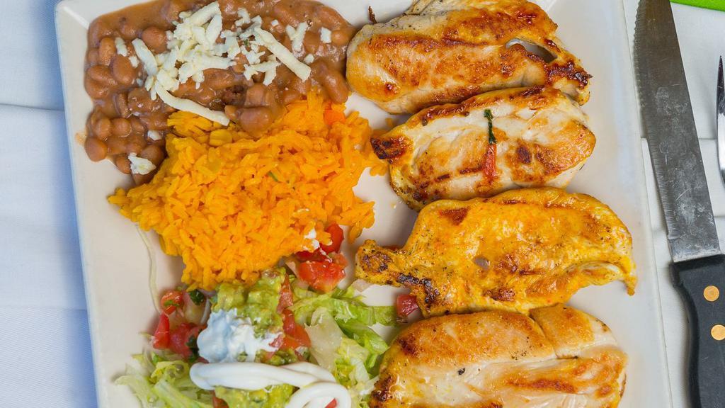 Pollo A La Plancha · Grilled chicken breast served with a side of yellow rice and refried beans or house salad.