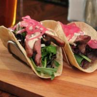 *Steak Tacos · grilled skirt steak, spring mix, queso fresco,  chili-lime crema & pickled red onion
