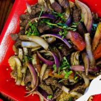 Tacu Tacu Con Lomo Saltado · Pan fried rice and beans cake topped with sliced beef cilantro and sauteed with red onions a...