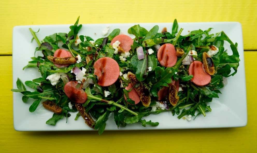 No Fig Deal Salad · Baby arugula and red onion tossed in lemon infused EVOO. Topped with goat cheese, figs, pickled radish, and basil. With a drizzle of balsamic glaze and Florida orange blossom honey for good measure.