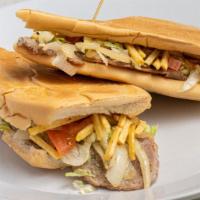 Pan Con Bistec · Thin-cut Palomilla steak topped with grilled onions, lettuce, tomatoes & potato sticks on to...