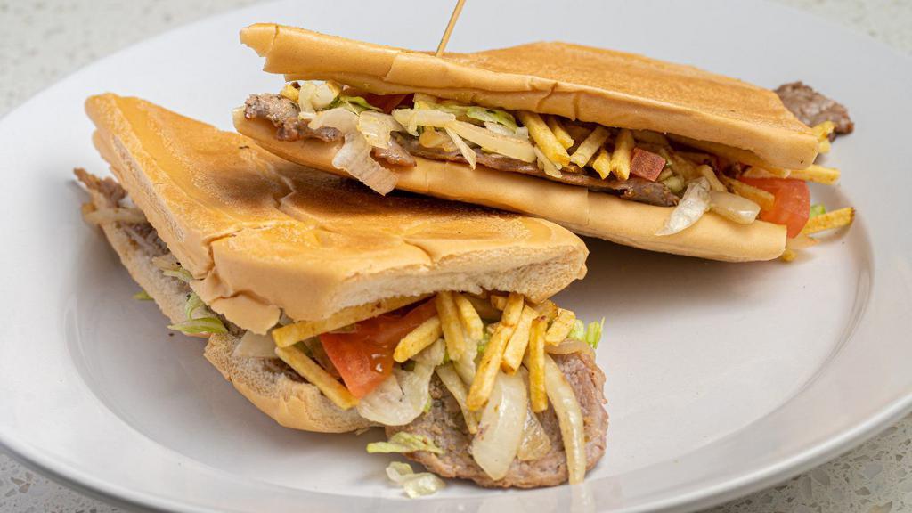 Pan Con Bistec · Thin-cut Palomilla steak topped with grilled onions, lettuce, tomatoes & potato sticks on toasted Cuban bread