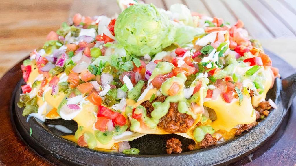 Supreme Tostada Nacho · Seasoned ground beef, cheese blend, yellow queso, refried beans, pico de gallo, fried jalapenos, lettuce, avocado lime salsita, sour cream and guacamole on top of our house made corn chips. Gluten free.