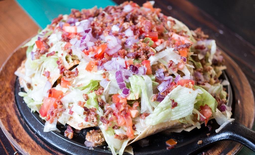 Nacho Average Burger Nacho · Seasoned ground beef, Applewood smoked bacon, yellow queso, red onions, tomatoes & shredded lettuce on top of our house-made corn chips. Gluten-free.