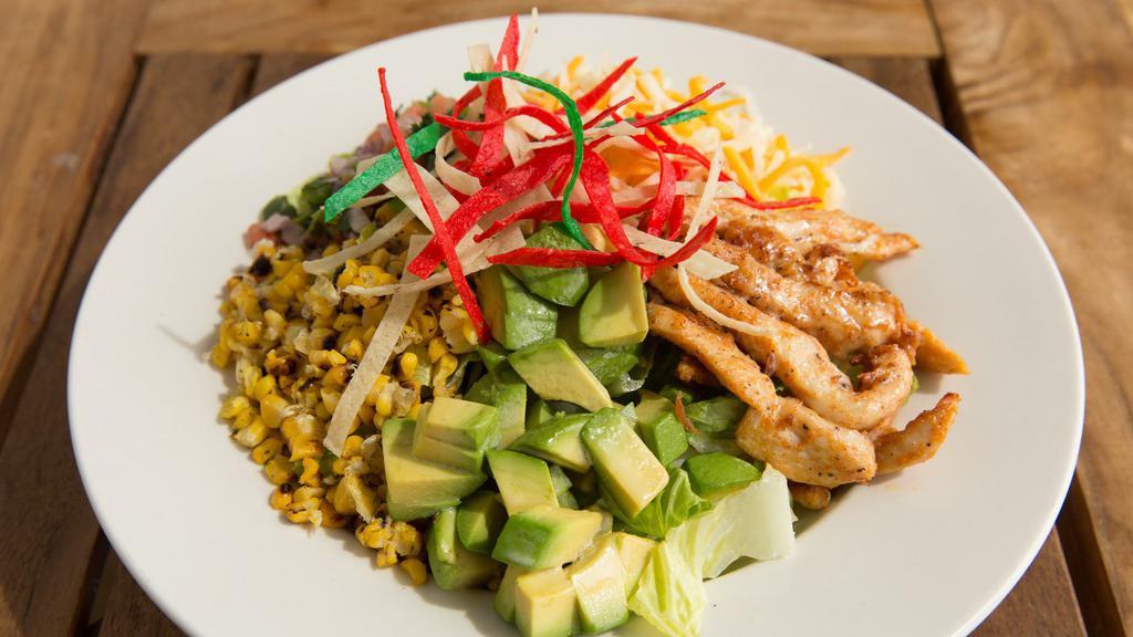 Mexi-Cobb Salad · Romaine hearts tossed in onion thyme vinaigrette and topped with marinated chicken strips, pico de gallo, cheese blend, corn, cucumbers, avocado, and tortilla strips.