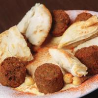 Falafel On A Platter · Crispy falafel balls served on a bed of  hummus with a side of tahini and pita.