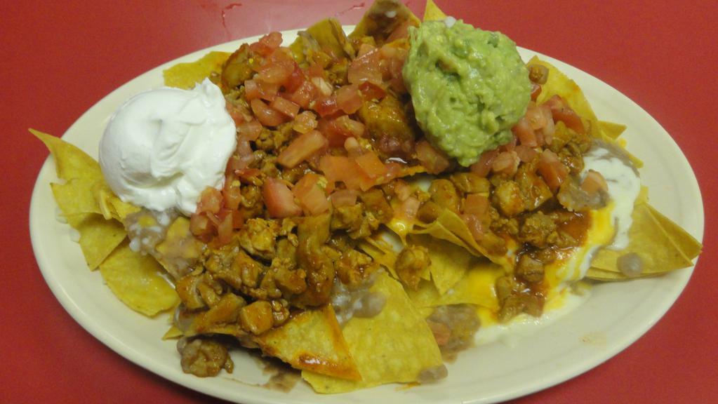 27) Nachos · Fried tortilla chips topped with beans, your choice of meat, melted mozzarella and cheddar cheese, tomato, sour cream and guacamole.