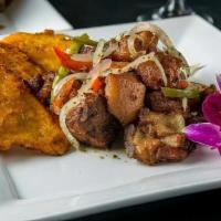 Griot · Marinated fried pork chunks topped with peppers and onions, mild or spicy. Served with one s...