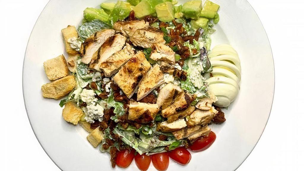 Cobb · Mixed greens and romaine, grilled chicken, bacon,. avocados, eggs, Bleu cheese, grape tomatoes, green. onions, pecans and croutons tossed in Bleu cheese. dressing.