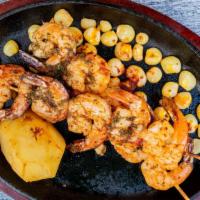 Brochetas De Camarones · Three grilled shrimp brochettes with Peruvian corn and boiled potato.