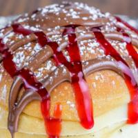 Nutella Bomba · Fresh made roll filled with Nutella and topped with raspberry sauce and powdered sugar.