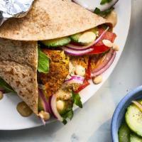 Falafel Sandwich · Falafel with hummus spread topped with  tomato and onion and a tahini lemon dressing,  are i...