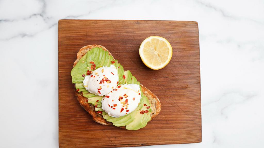 Poached · Two poached eggs served over multi-grain loaf topped with avocado slices, olive oil, lemon juice, and chili flakes.