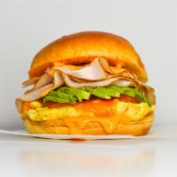 Brioche, Smoked Turkey, Egg & Avocado · 2 scrambled eggs, melted Cheddar cheese, smoked turkey, avocado, and Sriracha aioli in a war...