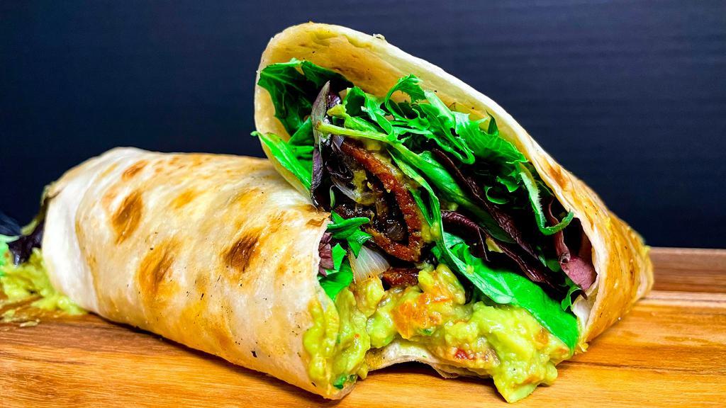 Guac Bacon Wrap · Homemade guacamole, hickory smoked tempeh bacon, tomatoes, grilled onions, mixed greens on a toasted wrap.