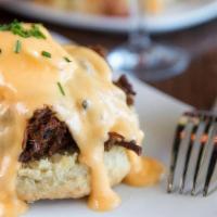 Eggs Cochon · Apple-braised pork debris over a housemade buttermilk biscuit with two poached eggs and holl...