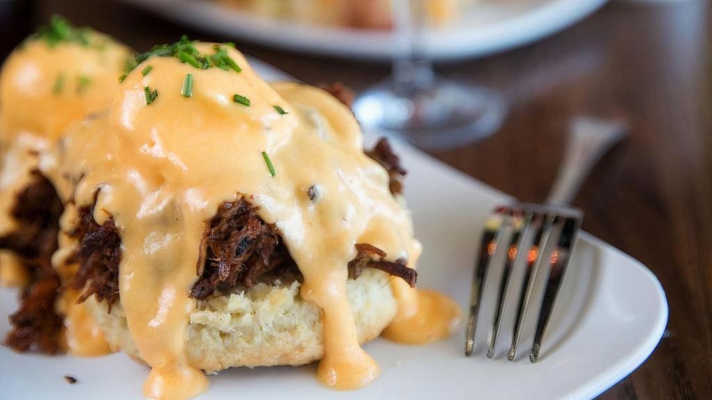 Eggs Cochon · Apple-braised pork debris over a housemade buttermilk biscuit with two poached eggs and hollandaise