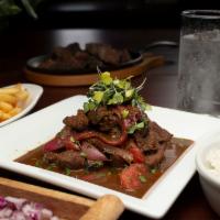 Lomo Saltado · Strips of steak sautéed with red onions, spices and tomatoes. Served with rice.