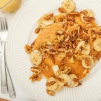 Banana Nut Pancakes · Two pancakes topped with walnuts, pecans and bananas.
