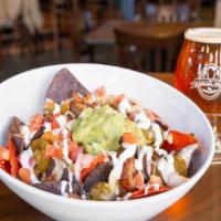 Bratchos · Tortilla chips topped with sliced bratwurst, beer cheese, sour cream, bacon, guacamole and p...