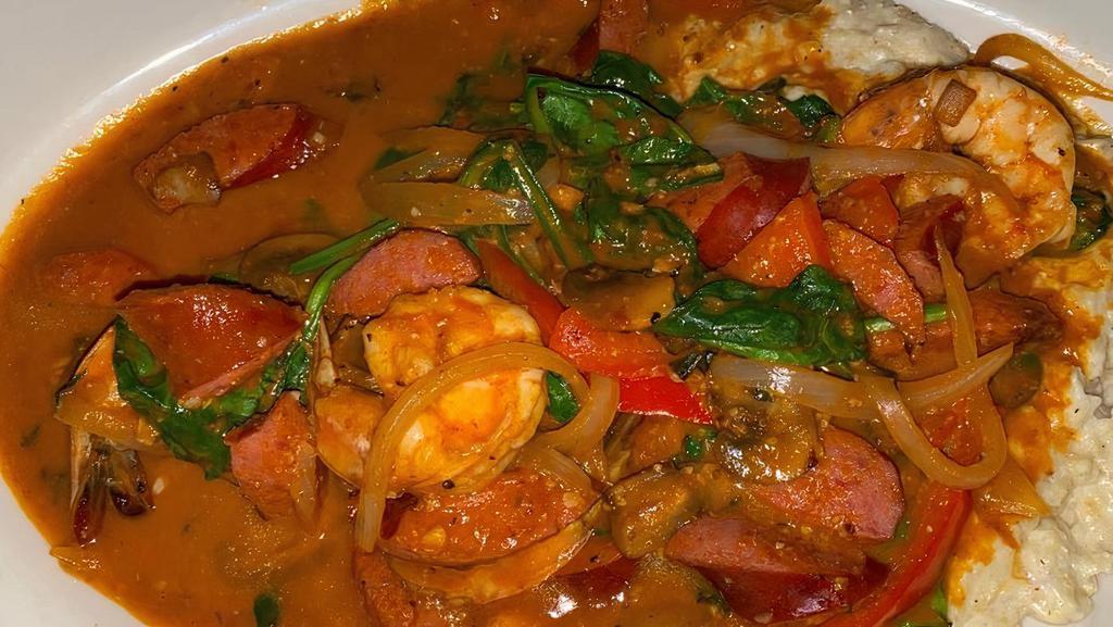 Shrimp & Grits · Grilled shrimps, beef andouille sausage, sautéed red peppers, and spinach, served in a red wine sauce on top of a bed of stone-ground grits mixed with smoked gouda cheese.