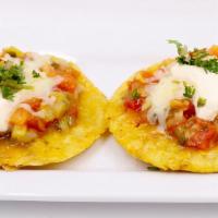 Patacones Costenos · Tostones with country sauce, cotija cheese topped with crema