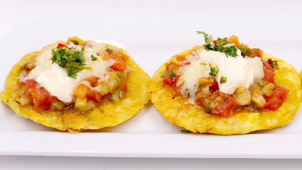 Patacones Costenos · Tostones with country sauce, cotija cheese topped with crema