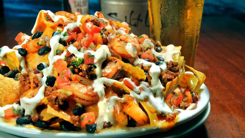 Shrimp & Chorizo Nachos. · Grilled shrimp and chorizo topped with corn, black beans, jack and cheddar cheese, pico and finished with a cilantro lime cream drizzle. Contains bacon.